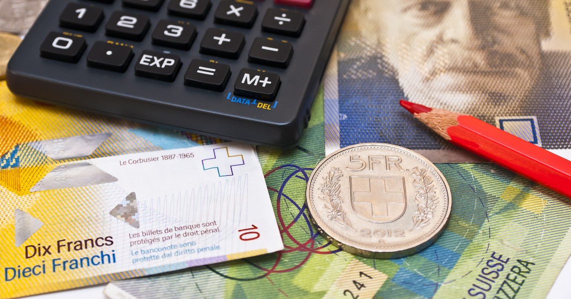 Symbolbild Produzenten- und Importpreisindex, Taschenrechner, roter Bundstift und fünf Franken Münze liegen auf Schweizer Banknoten