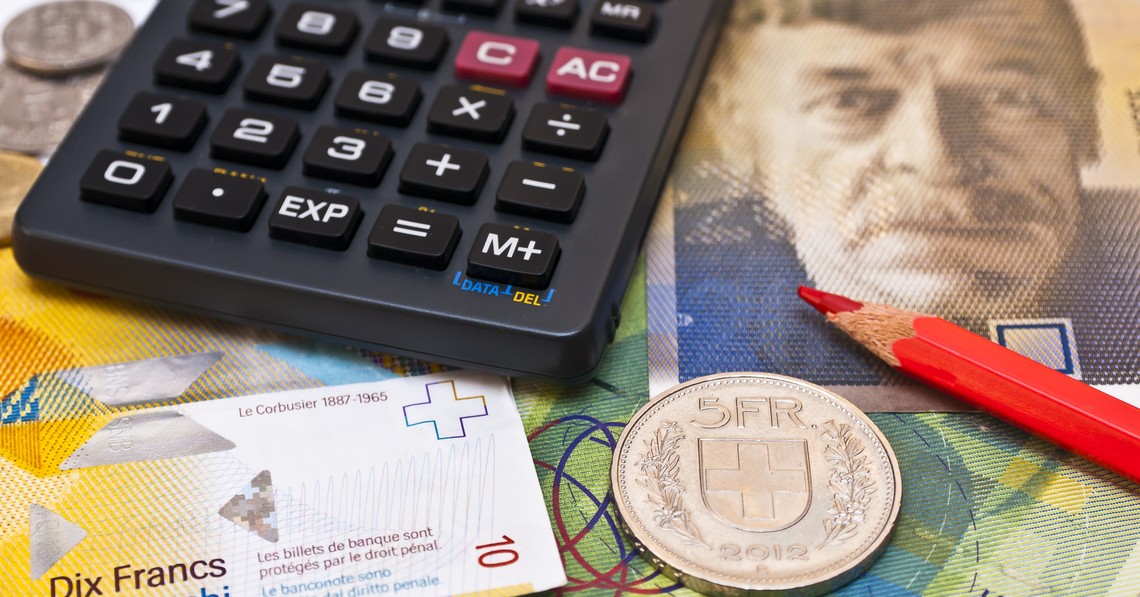 Symbolbild Produzenten- und Importpreisindex, Taschenrechner, roter Bundstift und fünf Franken Münze liegen auf Schweizer Banknoten