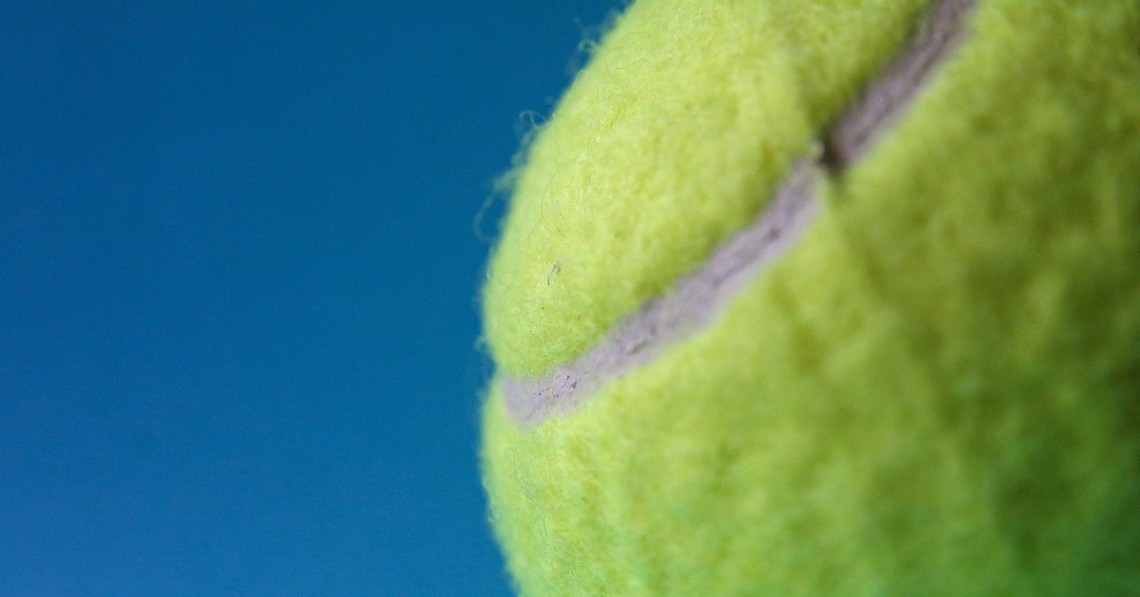 Gelber Tennisball auf blauem Hintergrund als Symbol für Resilienz