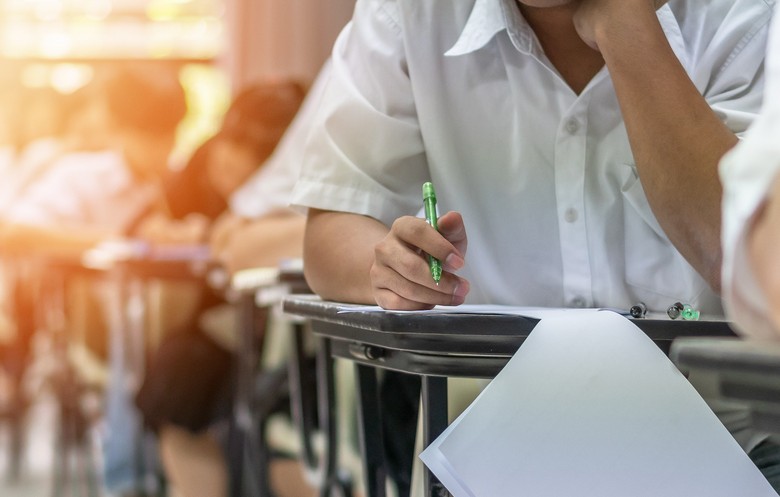 Schüler sitzen am Tisch und schreiben eine Prüfung