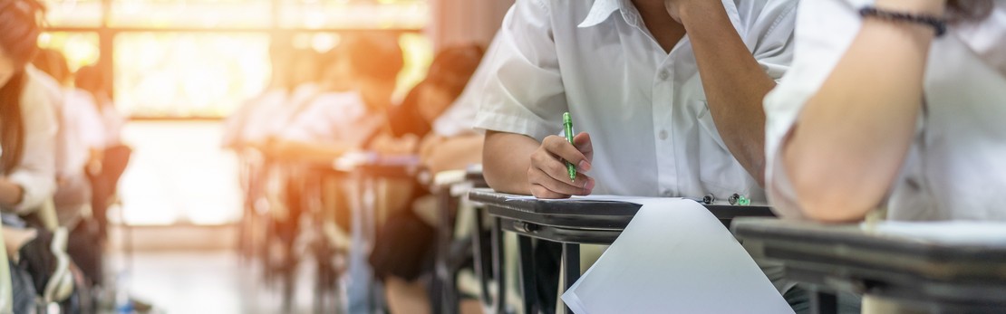 Schüler sitzen am Tisch und schreiben eine Prüfung